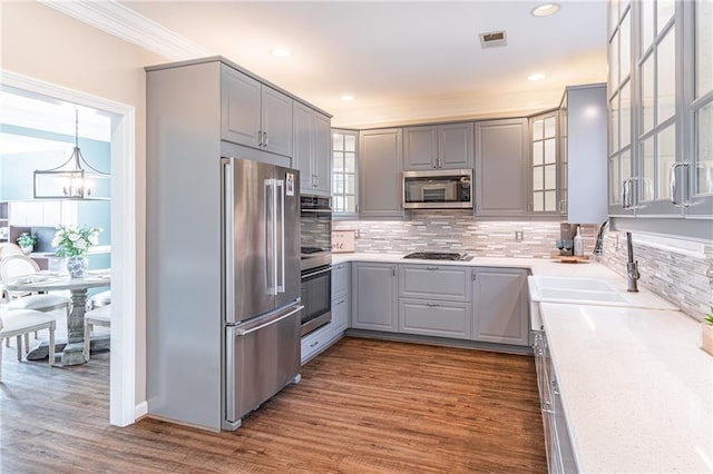 kitchen featuring appliances with stainless steel finishes, decorative light fixtures, dark hardwood / wood-style flooring, and gray cabinetry