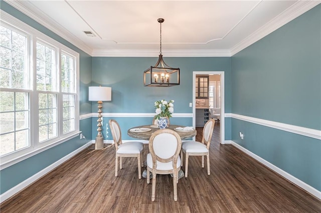 dining space featuring crown molding, a chandelier, and dark hardwood / wood-style flooring