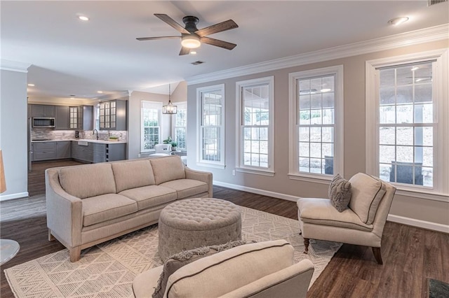 living room with hardwood / wood-style flooring, ornamental molding, sink, and ceiling fan with notable chandelier