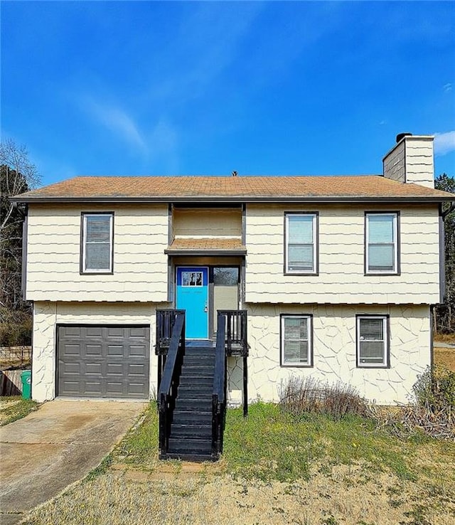 split foyer home featuring a garage, driveway, and a chimney