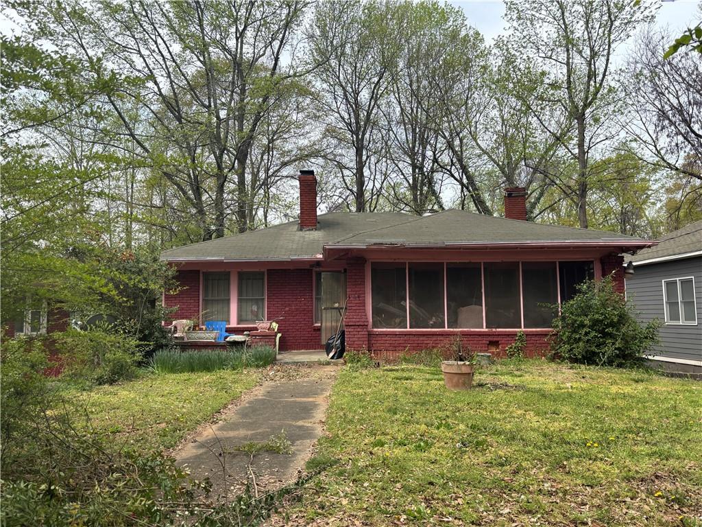 349 Hopkins St SW, Atlanta, GA 30310 - view of front of house with a sunroom, brick siding, a front yard, and a chimney