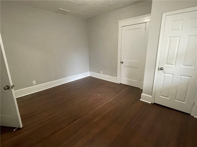 unfurnished bedroom featuring dark wood-type flooring and a textured ceiling