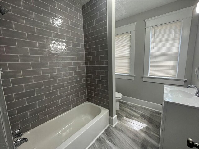 full bathroom with tiled shower / bath, toilet, hardwood / wood-style flooring, and vanity