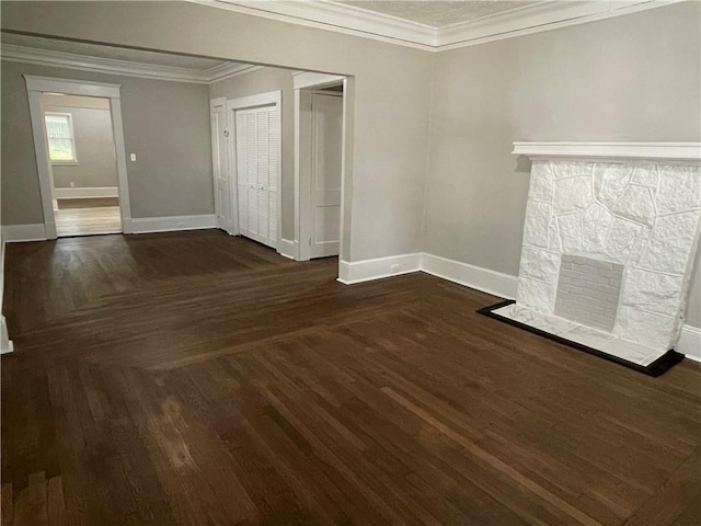 unfurnished living room featuring dark hardwood / wood-style floors, ornamental molding, and a stone fireplace