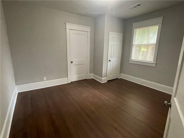 empty room with dark hardwood / wood-style floors and a textured ceiling