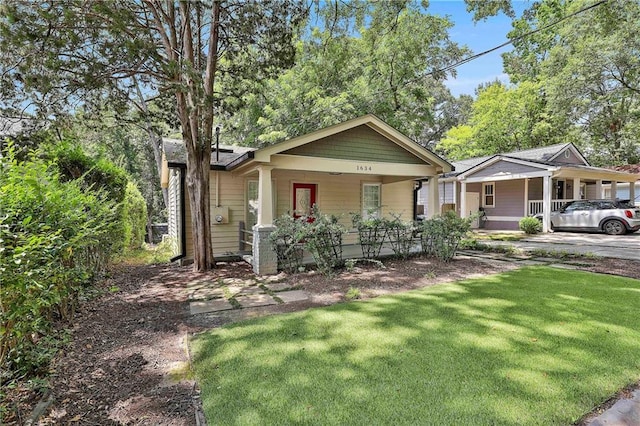 bungalow-style home featuring covered porch and a front lawn