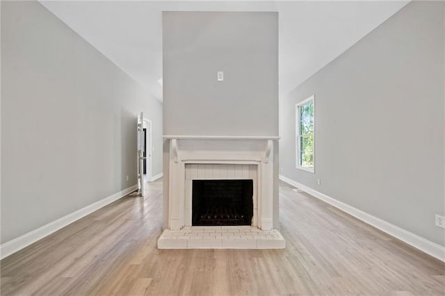 unfurnished living room featuring a brick fireplace and light hardwood / wood-style flooring