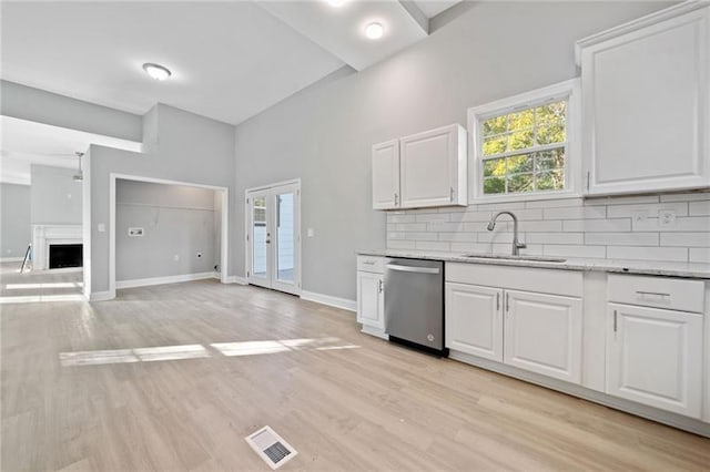 kitchen featuring dishwasher, white cabinetry, sink, backsplash, and light hardwood / wood-style flooring