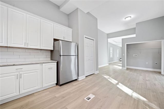 kitchen featuring tasteful backsplash, white cabinets, stainless steel refrigerator, and light hardwood / wood-style floors