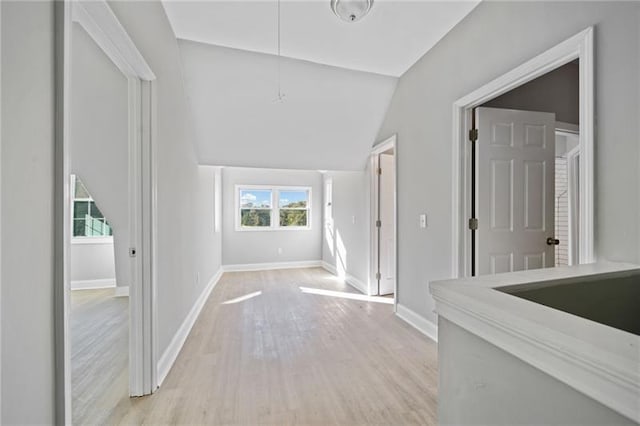 hall featuring plenty of natural light, light hardwood / wood-style flooring, and vaulted ceiling