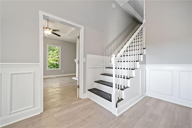 stairway featuring ceiling fan and hardwood / wood-style flooring