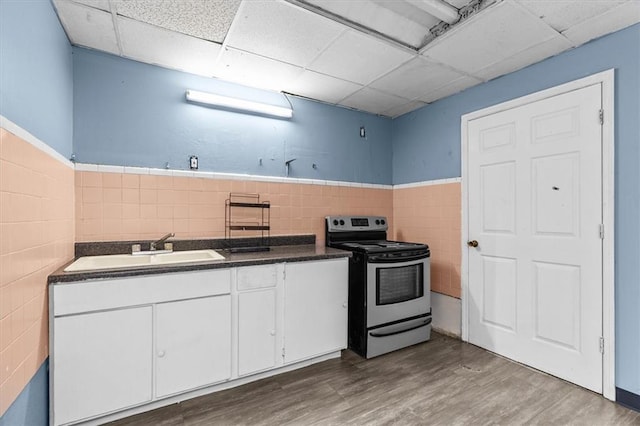 843 Mcafee St, Dalton, GA 30721 - kitchen with dark countertops, electric stove, a sink, tile walls, and white cabinets