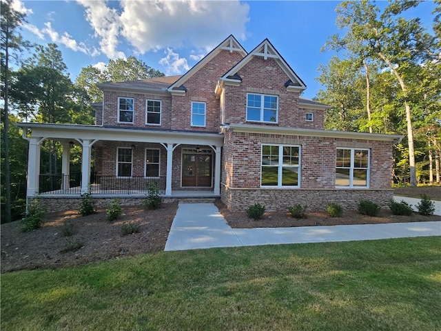 craftsman house with a porch, brick siding, and a front lawn