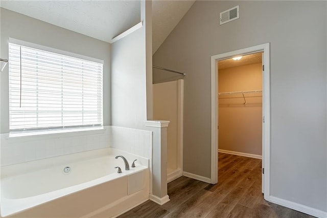 11143 Aliyah Dr, Hampton, GA 30228 - full bathroom with visible vents, a walk in closet, a garden tub, a stall shower, and wood finished floors