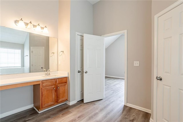 11143 Aliyah Dr, Hampton, GA 30228 - bathroom with vaulted ceiling, vanity, baseboards, and wood finished floors