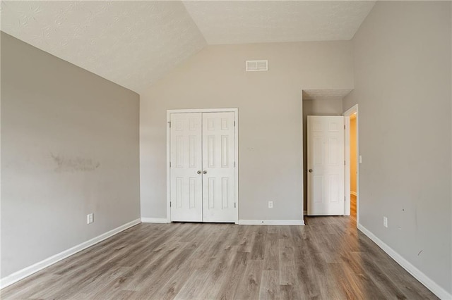 11143 Aliyah Dr, Hampton, GA 30228 - unfurnished bedroom featuring visible vents, baseboards, wood finished floors, a closet, and high vaulted ceiling
