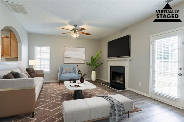 11143 Aliyah Dr, Hampton, GA 30228 - living room with visible vents, a fireplace with raised hearth, a ceiling fan, a textured ceiling, and wood finished floors