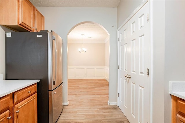 11143 Aliyah Dr, Hampton, GA 30228 - kitchen with brown cabinetry, light wood-type flooring, light countertops, freestanding refrigerator, and arched walkways