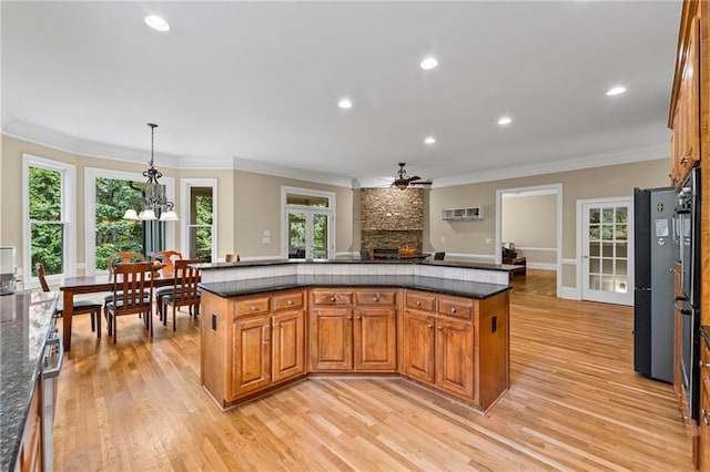 kitchen featuring ceiling fan, light wood finished floors, crown molding, brown cabinetry, and plenty of natural light
