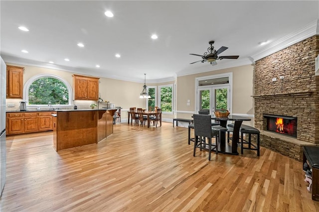 kitchen featuring healthy amount of natural light, a fireplace, light wood-style flooring, open floor plan, and recessed lighting