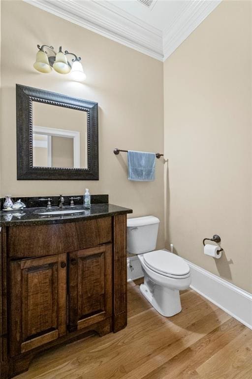 bathroom with wood finished floors, toilet, crown molding, baseboards, and vanity