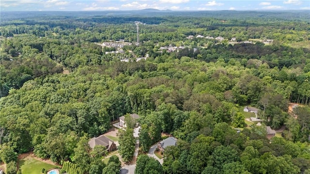 aerial view of property and surrounding area featuring a heavily wooded area