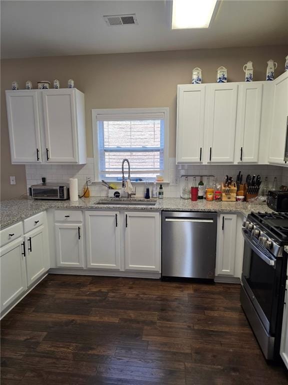 kitchen with a sink, stainless steel appliances, dark wood-type flooring, and white cabinetry