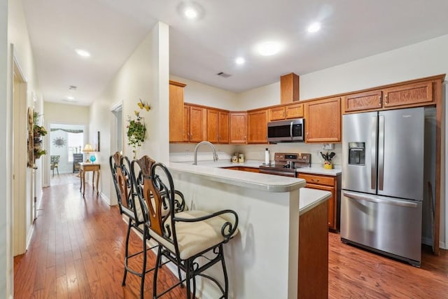 119 Holiday Rd, Unit Buford, GA 30518 - kitchen with appliances with stainless steel finishes, light countertops, a breakfast bar, wood finished floors, and a peninsula
