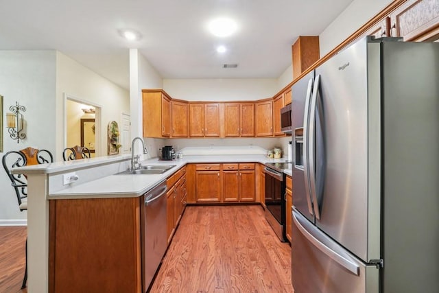 119 Holiday Rd, Unit Buford, GA 30518 - kitchen with stainless steel appliances, light wood finished floors, light countertops, a peninsula, and brown cabinets