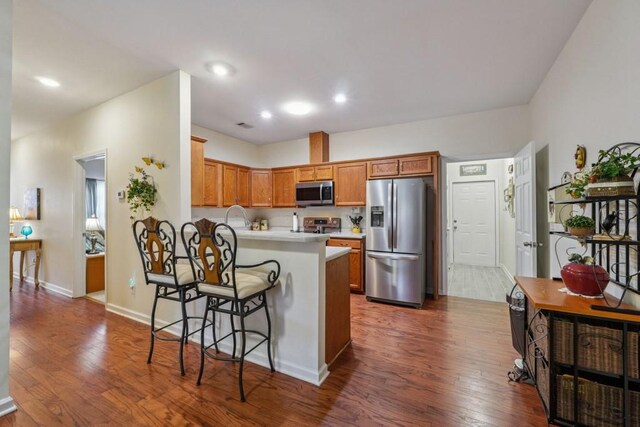 119 Holiday Rd, Unit Buford, GA 30518 - kitchen featuring stainless steel appliances, a breakfast bar area, a peninsula, dark wood-style flooring, and light countertops