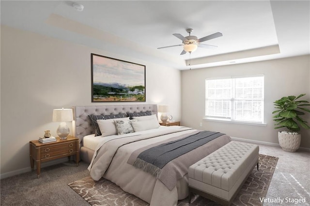 carpeted bedroom with a raised ceiling and ceiling fan