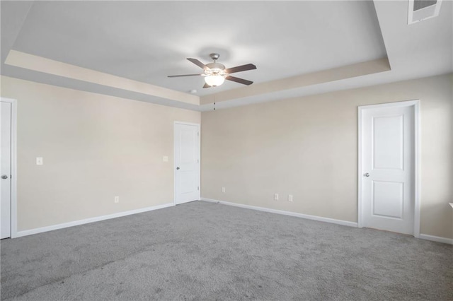 spare room featuring carpet flooring, ceiling fan, and a tray ceiling