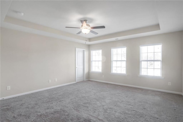 carpeted spare room with ceiling fan and a tray ceiling