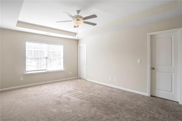 carpeted empty room featuring ceiling fan and a tray ceiling