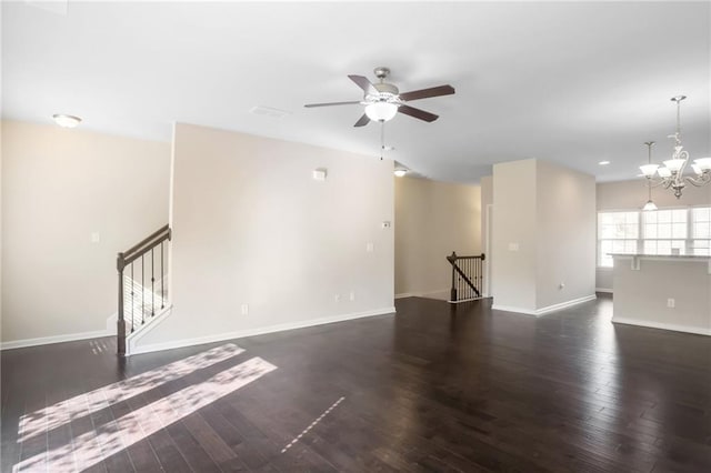 spare room with ceiling fan with notable chandelier and dark hardwood / wood-style floors