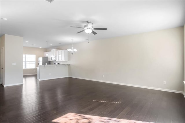 unfurnished living room featuring ceiling fan with notable chandelier and dark wood-type flooring