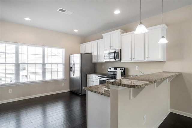 kitchen featuring pendant lighting, stainless steel appliances, kitchen peninsula, and white cabinets