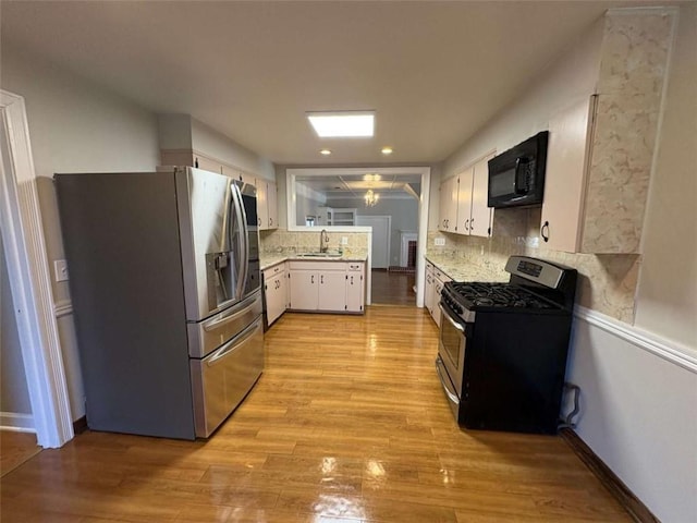 2807 Mcclave Dr, Doraville, GA 30340 - kitchen with appliances with stainless steel finishes, a sink, light countertops, white cabinetry, and decorative backsplash