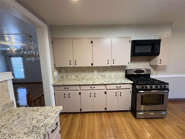 2807 Mcclave Dr, Doraville, GA 30340 - kitchen with gas range, black microwave, a chandelier, light wood-style floors, and decorative backsplash