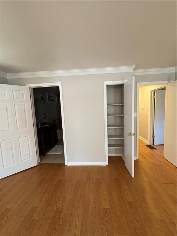 2807 Mcclave Dr, Doraville, GA 30340 - unfurnished bedroom with wood finished floors, baseboards, crown molding, a closet, and ensuite bath