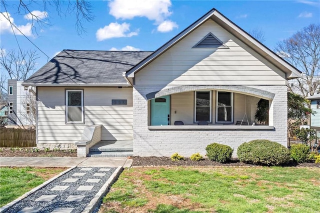 bungalow-style home featuring a front lawn, fence, and brick siding