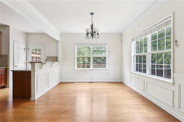 626 Pecan Knoll Dr Unit 13, Marietta, GA 30008 - unfurnished dining area featuring plenty of natural light, a chandelier, light wood-style flooring, crown molding, and a wainscoted wall
