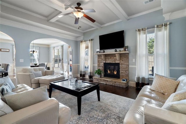 living room featuring crown molding, beamed ceiling, ceiling fan, a fireplace, and hardwood / wood-style floors