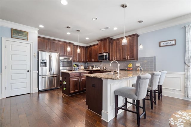 kitchen featuring dark hardwood / wood-style floors, a kitchen breakfast bar, hanging light fixtures, kitchen peninsula, and stainless steel appliances