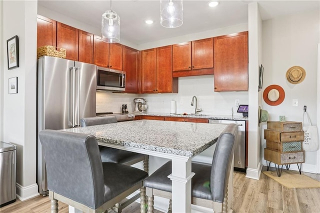840 United Ave SE Unit 205, Atlanta, GA 30312 - kitchen with appliances with stainless steel finishes, light stone counters, light wood-type flooring, a center island, and a kitchen bar