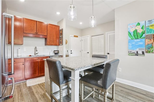 840 United Ave SE Unit 205, Atlanta, GA 30312 - kitchen featuring light wood-style flooring, light stone counters, a breakfast bar, hanging light fixtures, and recessed lighting