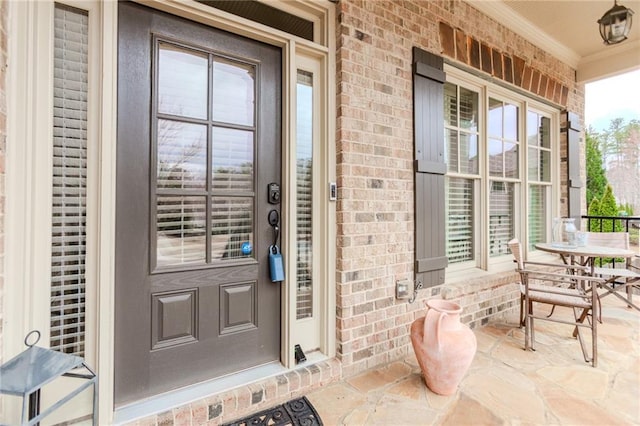 view of exterior entry featuring covered porch and brick siding