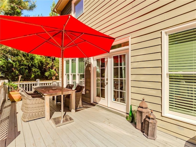 wooden terrace with outdoor dining area and french doors