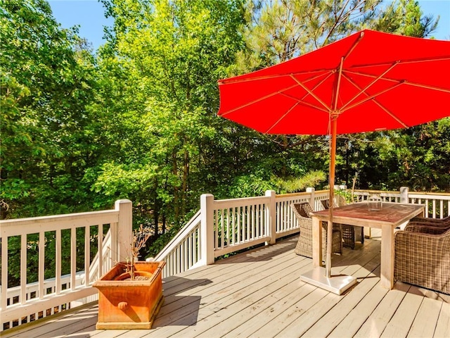 wooden deck with outdoor dining space and view of wooded area