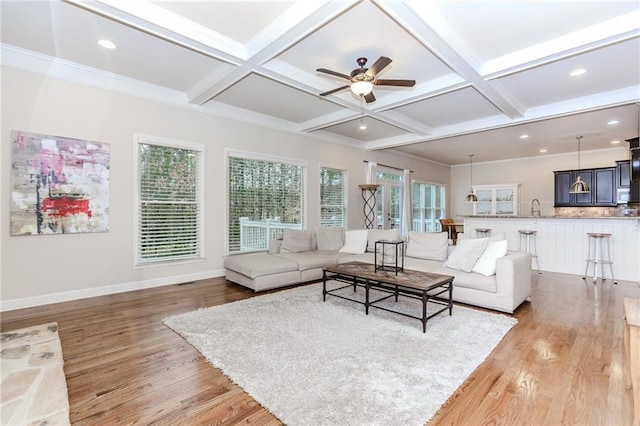 living room featuring light wood-type flooring, coffered ceiling, healthy amount of natural light, ceiling fan, and beamed ceiling